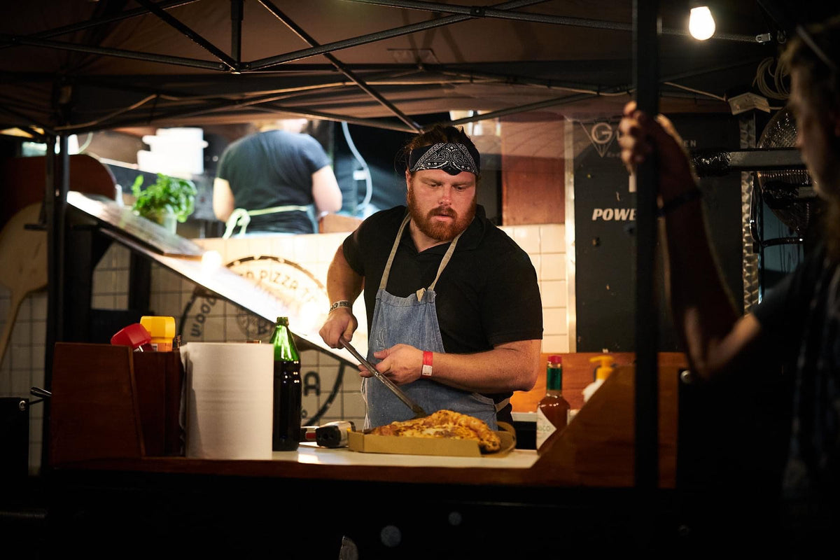 Un cocinero prepara pizza en la cocina de un food truck